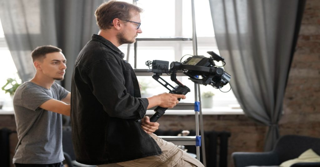 Two men work on a camera in a living room, focusing on techniques for 360-degree video production.