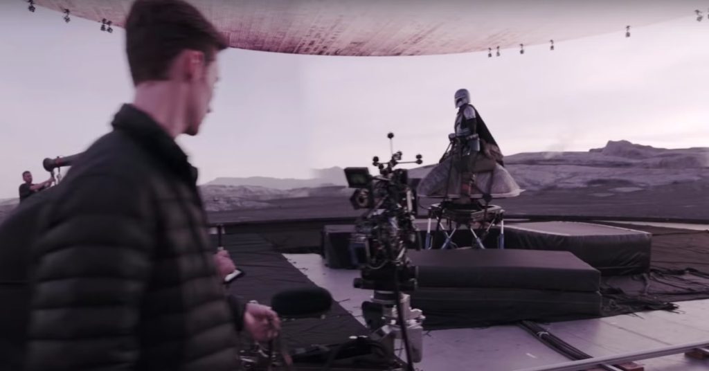 A man stands on the VFX set, showcasing matte painting technique.