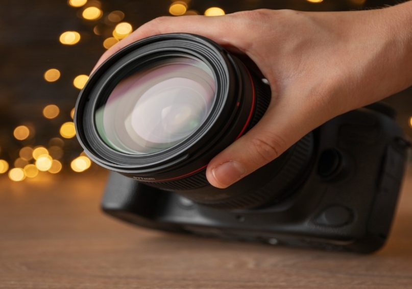 A person holding a camera with a lens, demonstrating advanced camera techniques for corporate video production.
