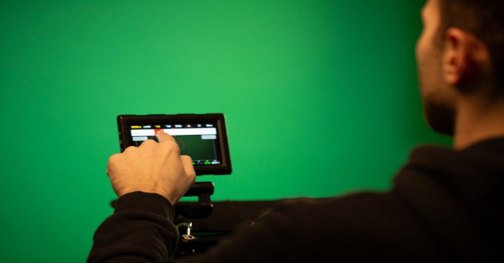 A man changing the settings of his camera to shoot in a green screen setting. 