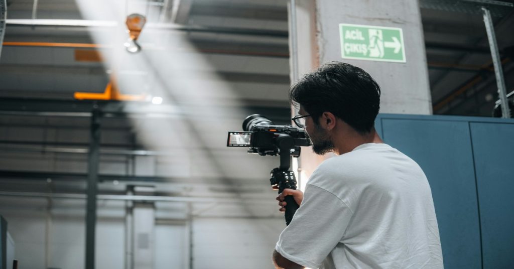 A man using gimbal in a warehouse for shooting to showcase professional quality of the video.