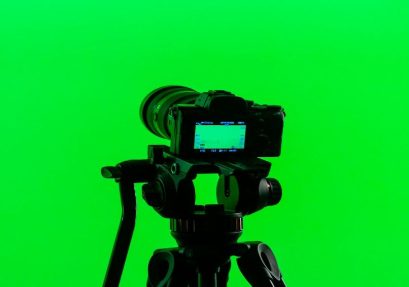 Shooting with a Green Screen for Corporate Video Production A camera on a tripod facing a green screen, prepared for filming corporate videos.