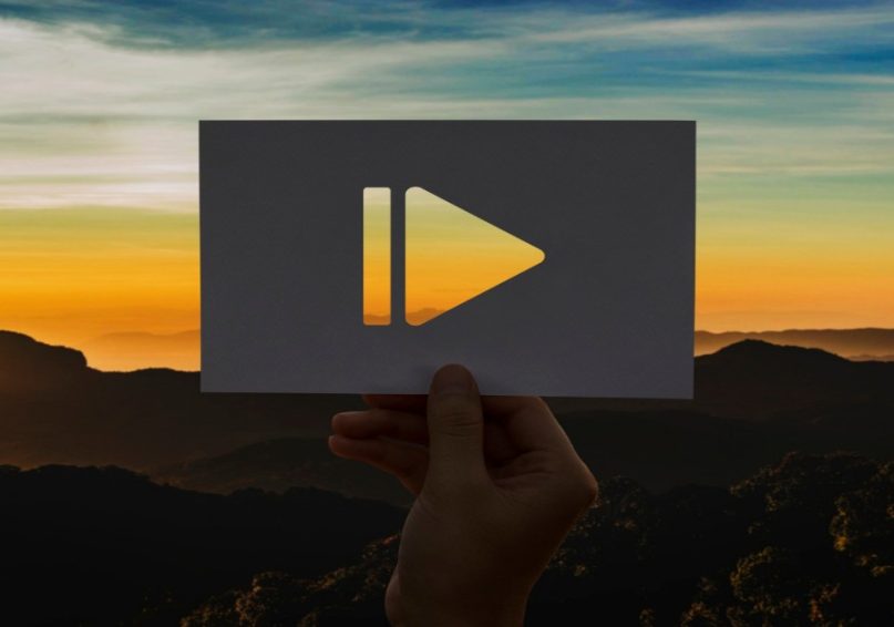 Play button on paper with a sunset scene, illustrating the role of corporate videos in enhancing business.