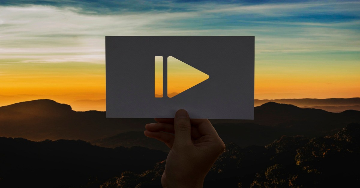 Play button on paper with a sunset scene, illustrating the role of corporate videos in enhancing business.